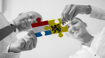 Twee mensen houden puzzelstukjes Vlaanderen en Nederland vast